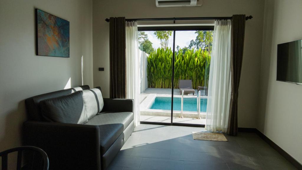 洛坤府Toledo Pool Villa的带沙发和滑动玻璃门的客厅
