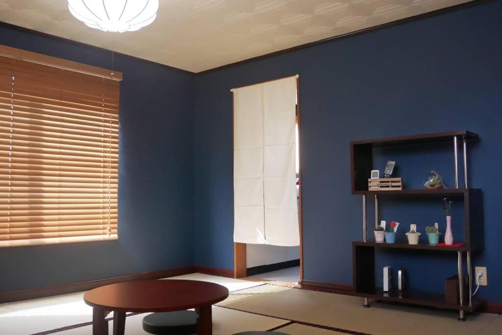 淡路民泊 桔梗的一间设有一张桌子和一把椅子的蓝色墙壁客房