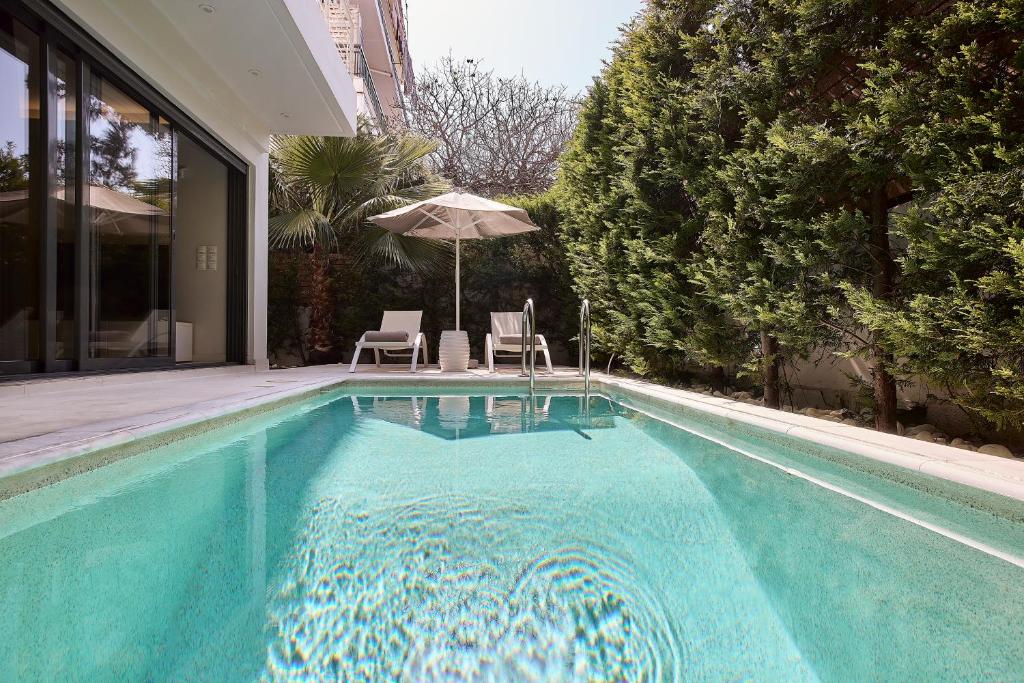 雅典Elaia Luxury Condo Glyfada的一个带两把椅子和遮阳伞的游泳池