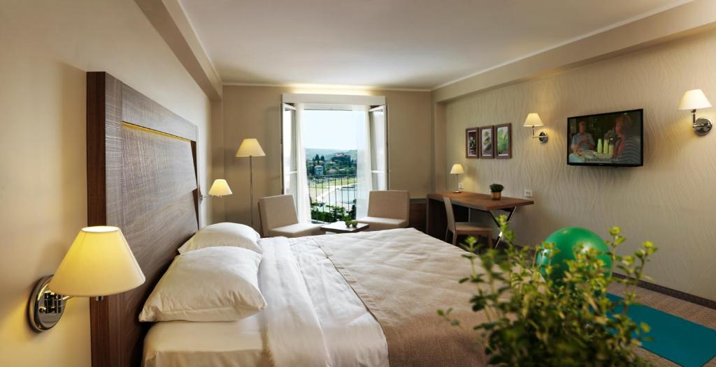 波尔托罗Wellness Hotel Apollo – Terme & Wellness LifeClass的酒店客房设有床和窗户。
