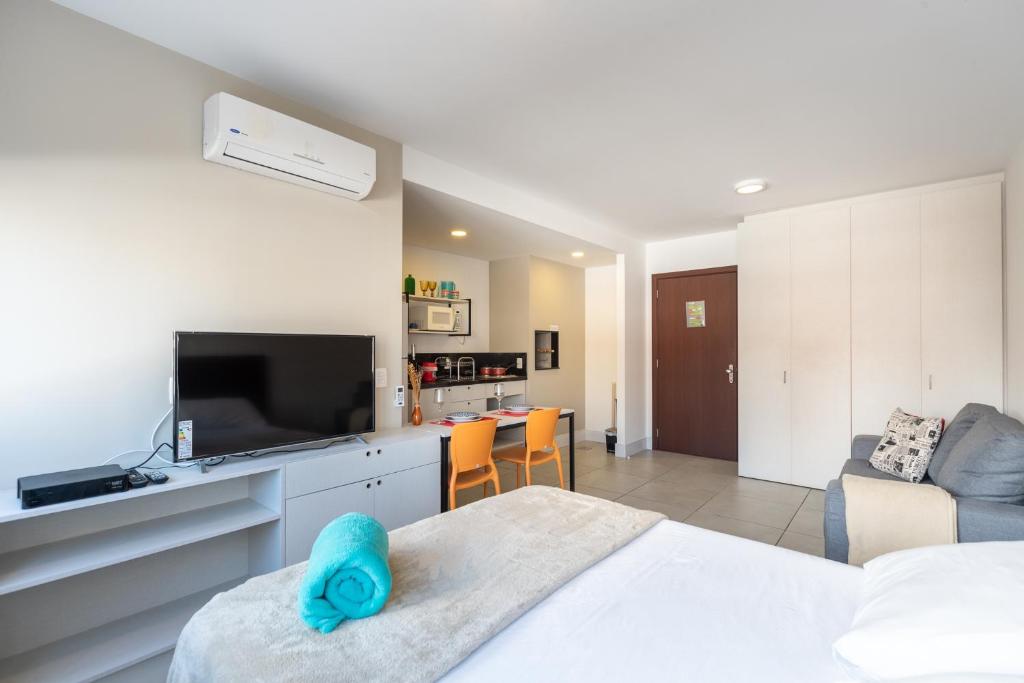 阿雷格里港Apartamento incrível Pueblo 595的一间卧室设有一张床和一台电视,还设有一间客厅。