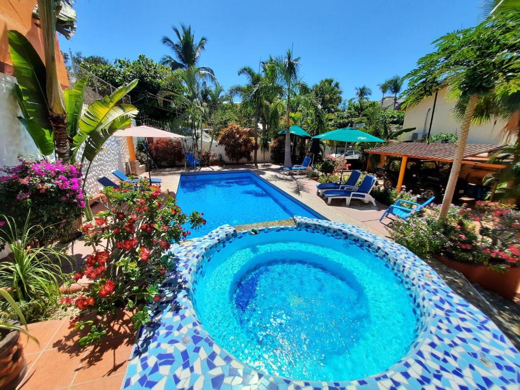 埃斯孔迪多港Hotelito Swiss Oasis -Solo Adultos - Adults only的花草繁茂的院子内的游泳池