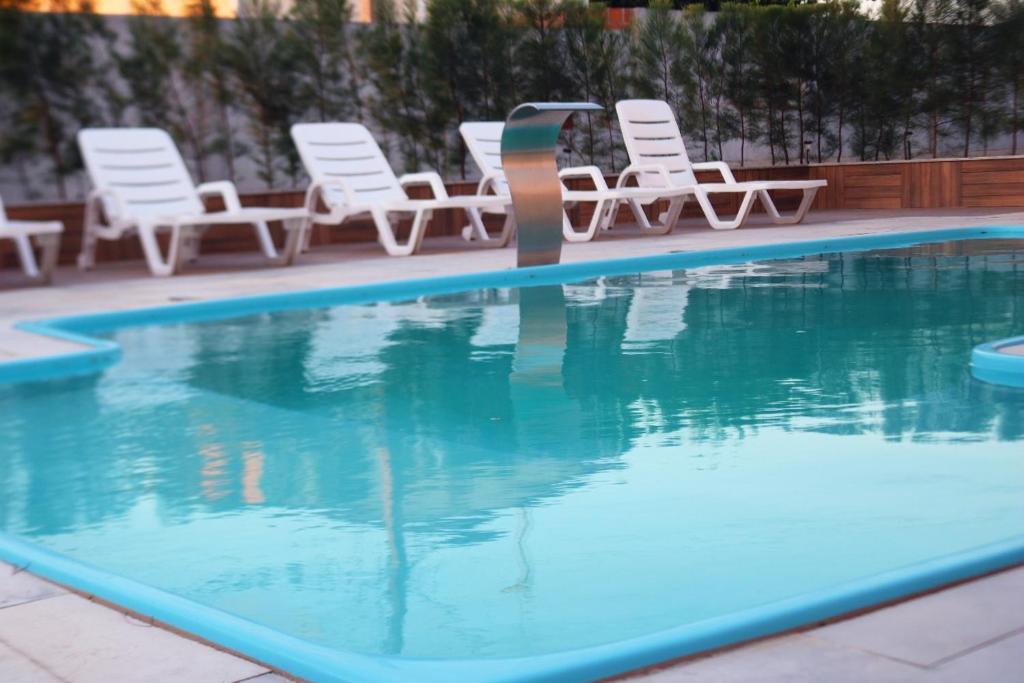 皮拉尼亚斯Dunen Hotel的一个带白色椅子的游泳池以及一组