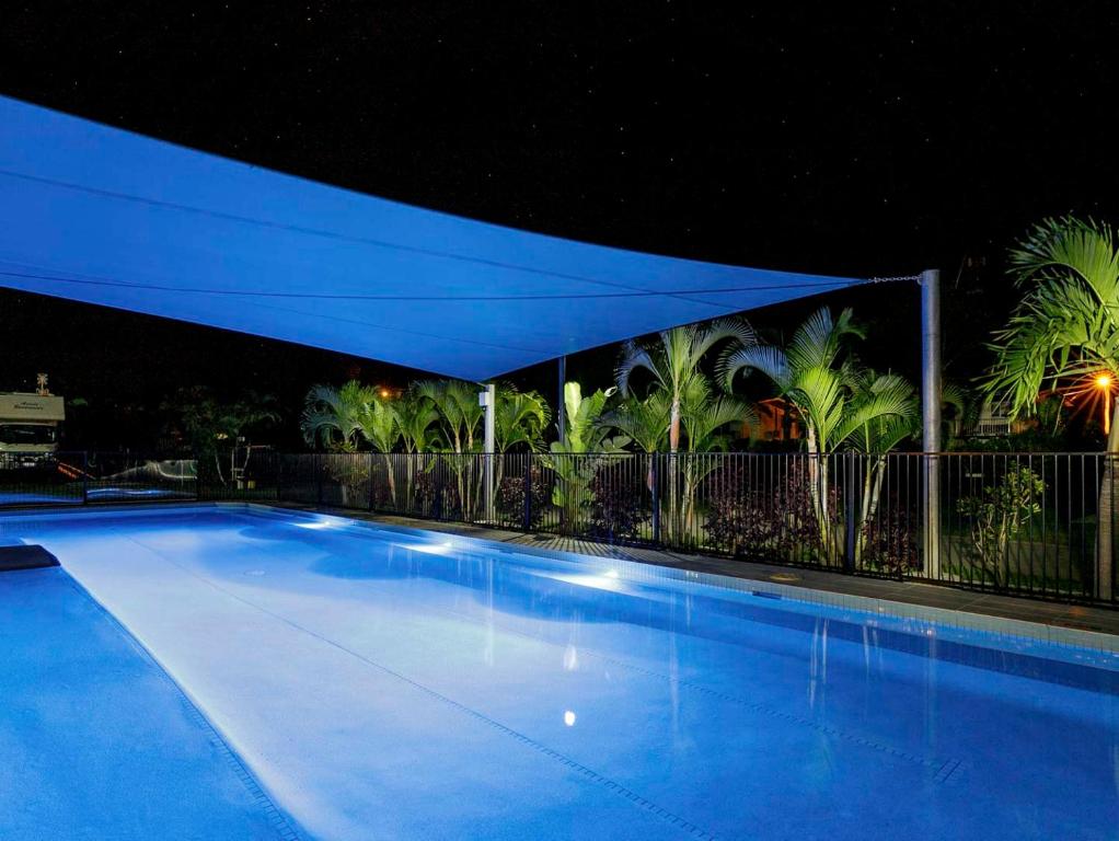 鲍恩皇后海滩旅游村酒店的夜间大型游泳池,有蓝色的天篷