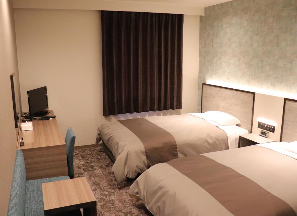 高知Tourist Inn Kochi的酒店客房配有两张床和一张书桌