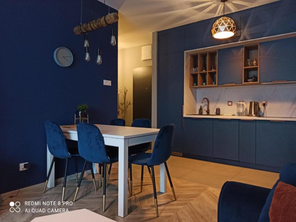 罗兹Nowoczesny Apartament przy Manufakturze z parkingiem podziemnym i klimatyzacją的一间拥有蓝色墙壁和白色桌椅的用餐室