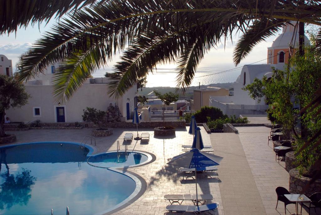 费拉Anatoli Hotel & Spa的一座带椅子和遮阳伞的游泳池位于一座建筑旁边