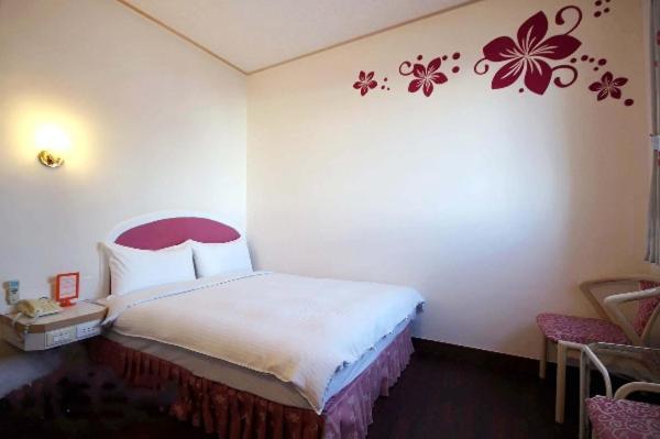 台东旅行家商务会馆的卧室配有一张挂着红花的床。