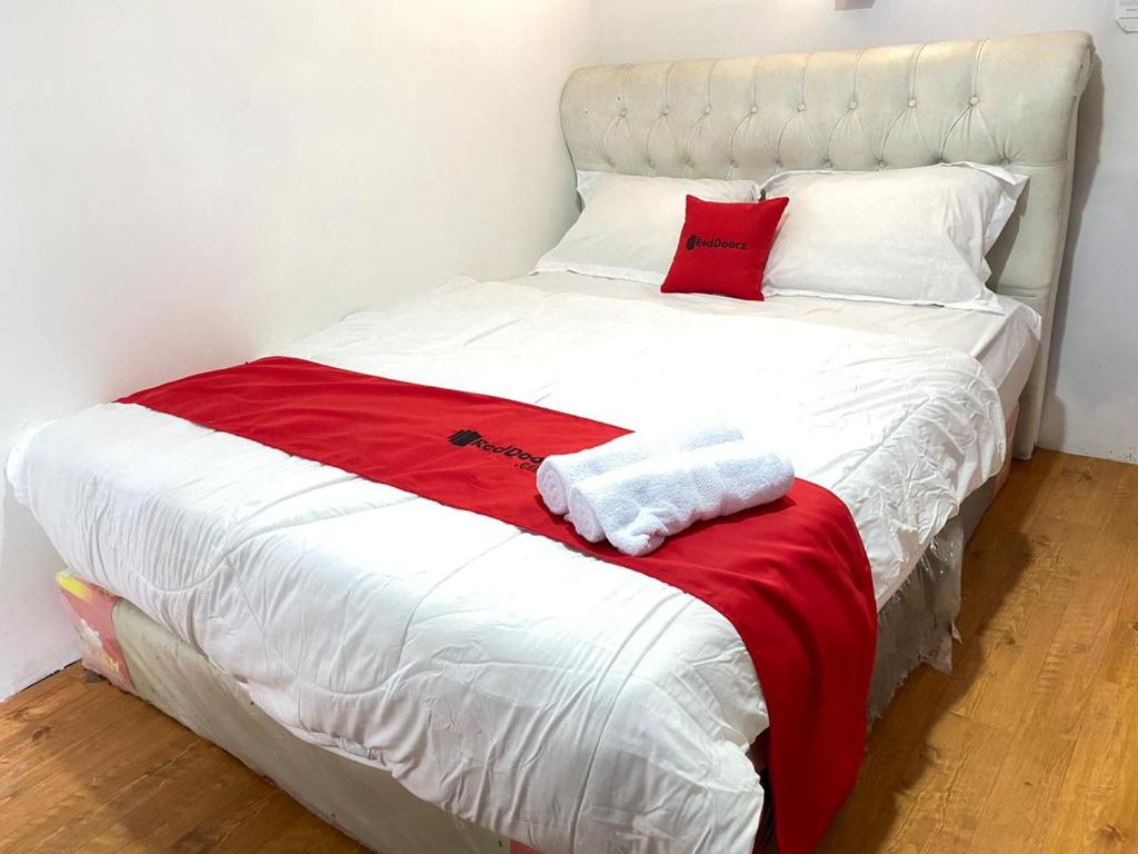 LampungRedDoorz Plus @ Puncak Mas Cottage的白色的床,上面有红色和白色的毛巾