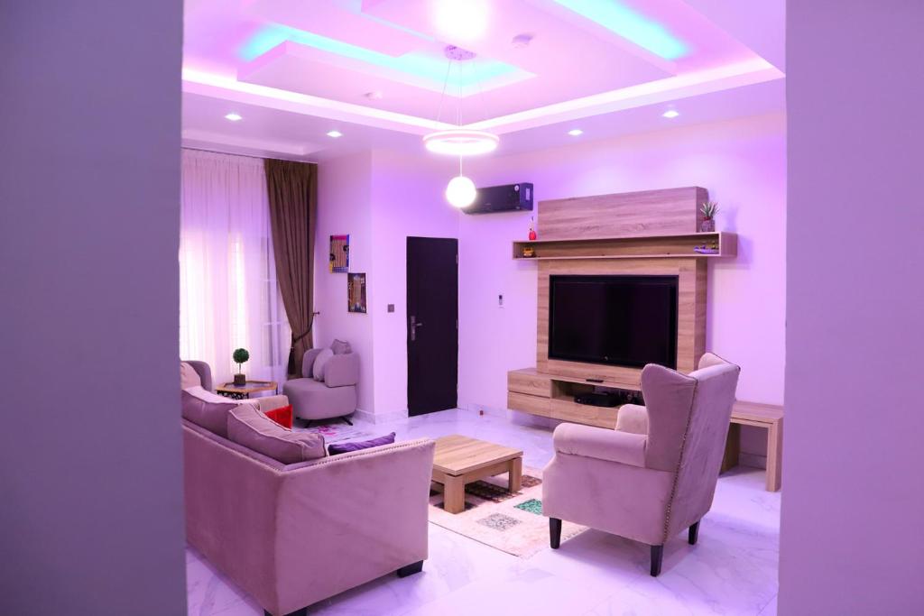 阿布贾Rhodabode Apartments. A Luxury 3 bedroom bungalow.的客厅设有紫色墙壁、电视和椅子