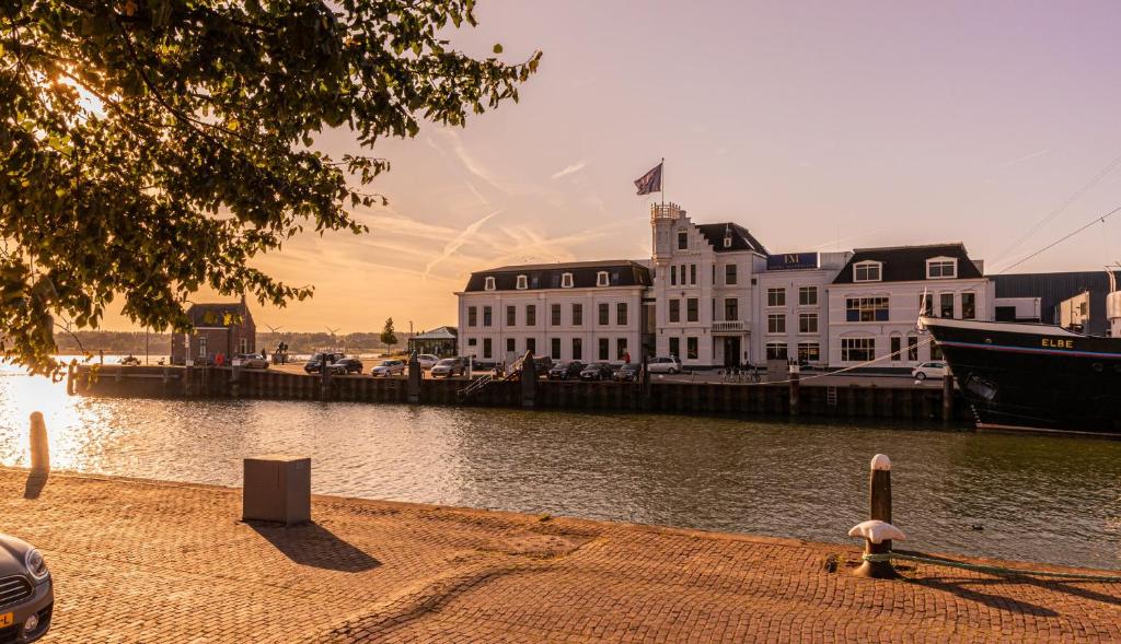 马斯劳斯Hotel Maassluis的水体旁的白色大建筑