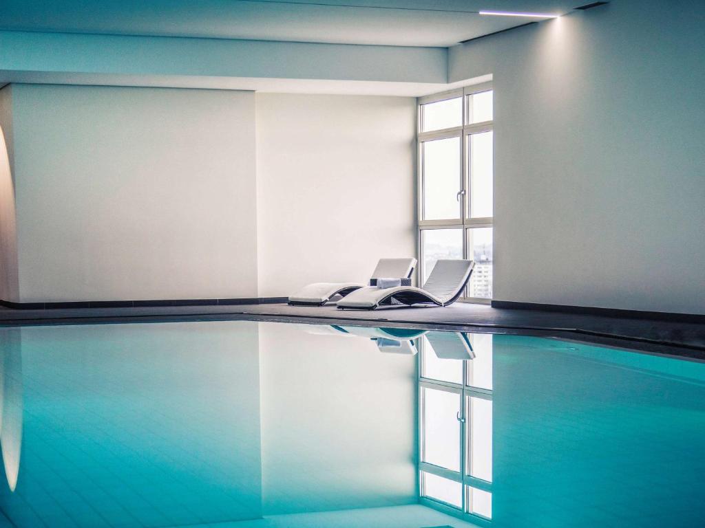 吕登沙伊德吕登沙伊德美居酒店的一个带两把椅子和窗户的游泳池