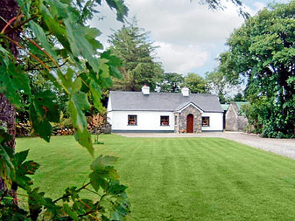 卡斯尔巴Clydagh Lodge的白色的房子,设有大院子和绿色草坪