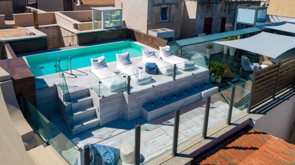 特拉帕尼Azzoli Trapani - Apartments&Skypool - Adults Only的享有带白色躺椅的游泳池的顶部景致