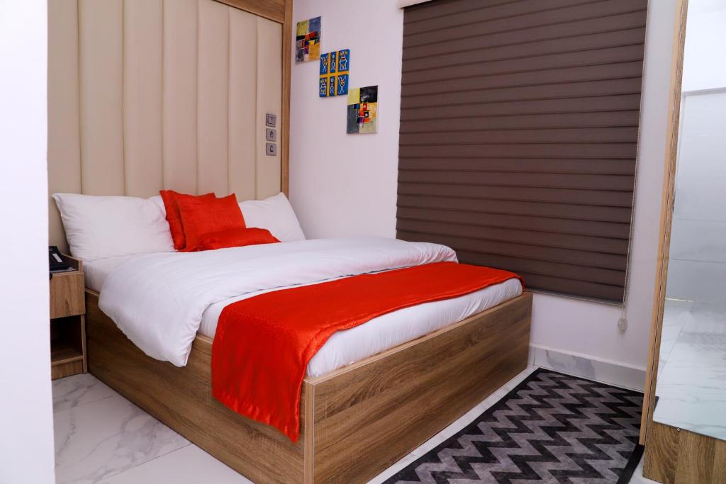 阿布贾GAZANIA CLASSIC SUITE, RHODABODE APT.的一间卧室配有一张床铺,床上铺有红色毯子