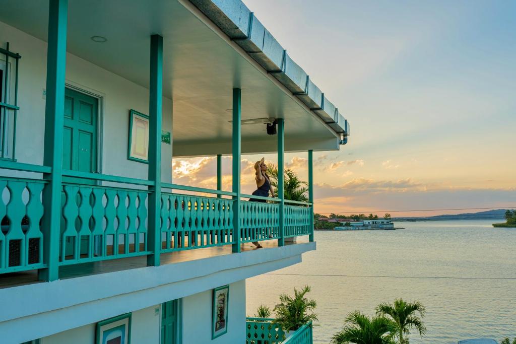 弗洛勒斯Hotel Casa Turquesa的站在一个眺望着水面的阳台上的女人