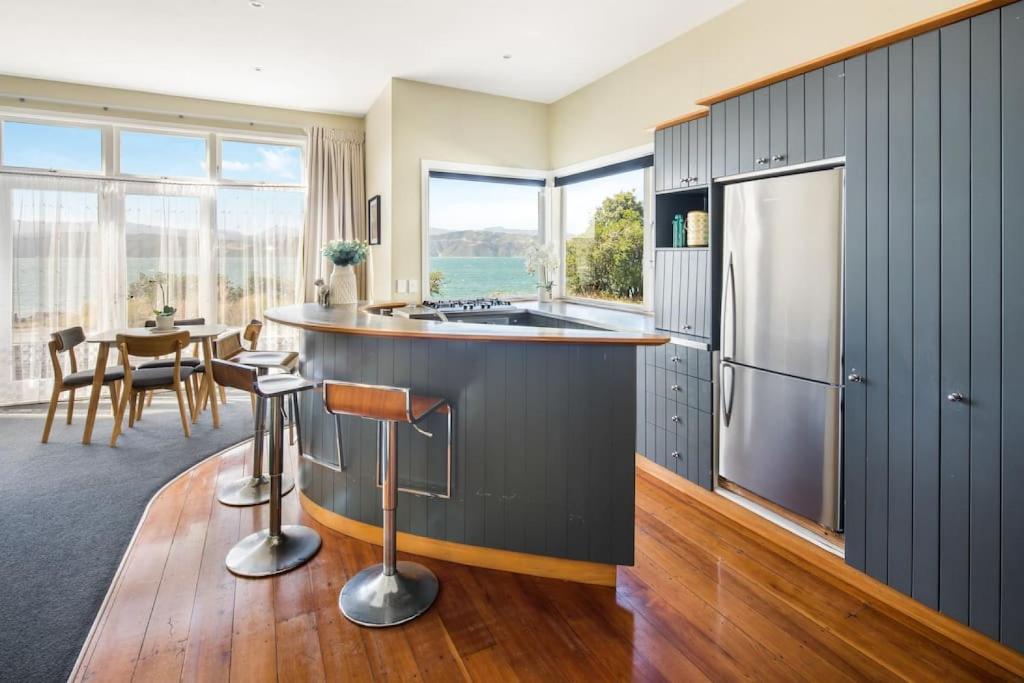 惠灵顿Waterfront 2-bed cottage, Karaka Bays的厨房配有不锈钢冰箱和桌子