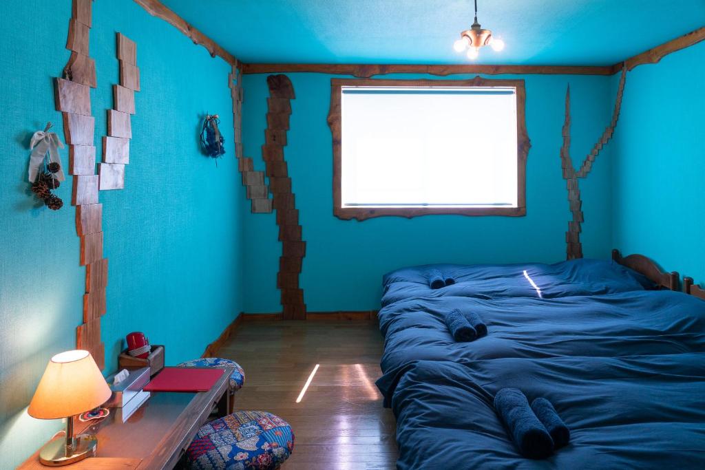 NishinaLodge Mondo的一间拥有蓝色墙壁、一张床和窗户的客房