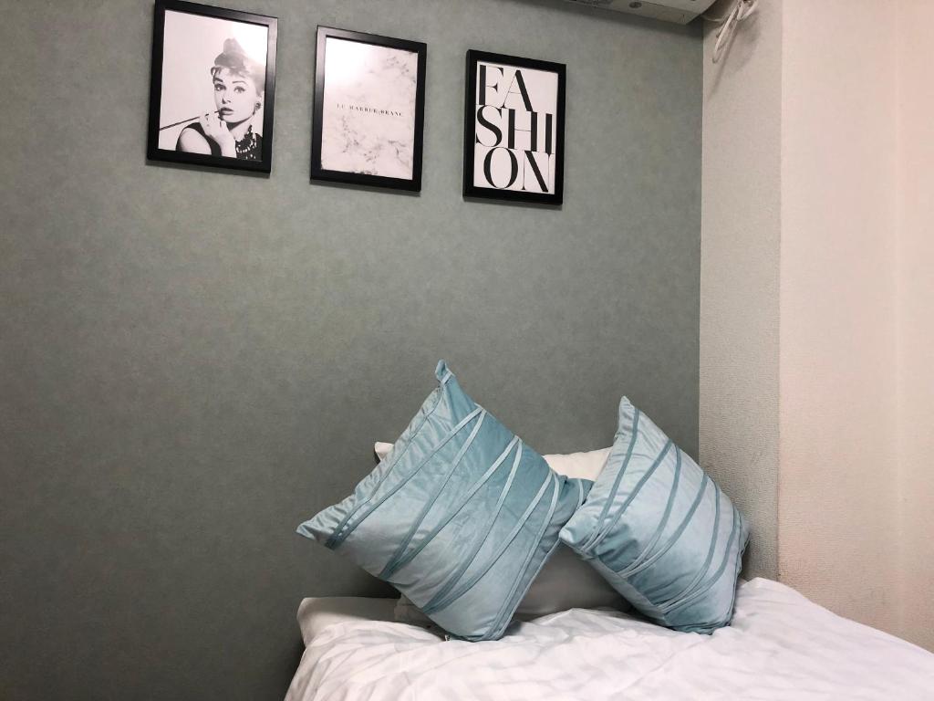 东京Fact Dream House 新宿三丁目徒歩3分色々揃うワンルーム的卧室配有三幅墙上照片和一张带枕头的床