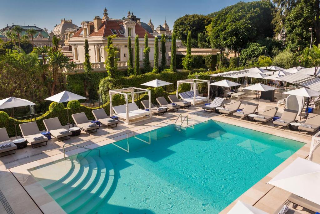 蒙特卡罗Hôtel Métropole Monte-Carlo - Deux restaurants étoilés的一座带躺椅的游泳池和一座建筑