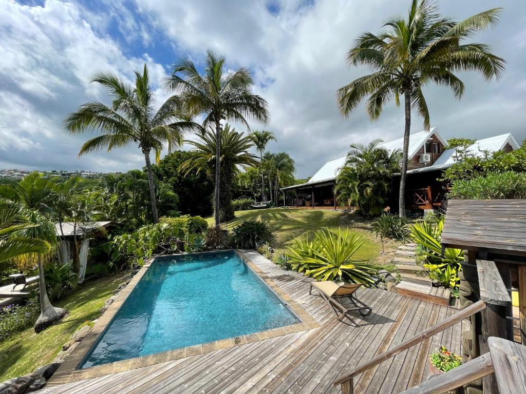圣吉尔莱班Villa Maido Luxe的一座棕榈树室外游泳池和一座房子