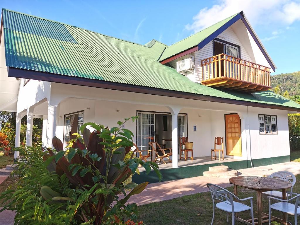 拉迪格岛CHEZ MARVA Grande Villa COCO 3 à 12 personnes的绿色屋顶房屋,配有桌椅