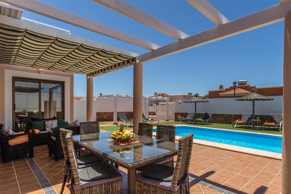 科斯塔德安提瓜Villa with private pool, near beach and golf Caleta de Fuste- Villa Charlotte的一个带桌椅的庭院和一个游泳池