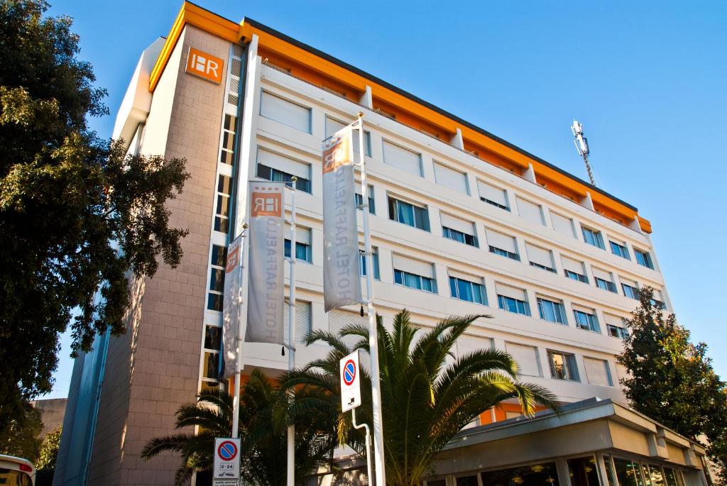 佛罗伦萨拉菲罗酒店的一座高大的白色建筑,前面有棕榈树