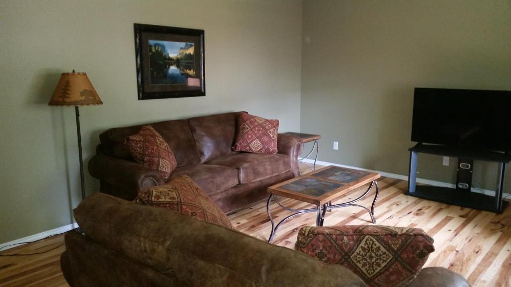 西黄石Geyser Mountain Home的客厅配有棕色沙发和桌子
