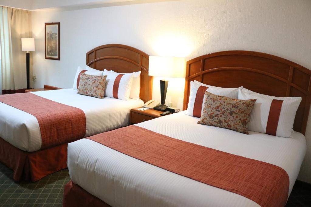 帕丘卡德索托Mision Pachuca的酒店客房,设有两张床和一盏灯