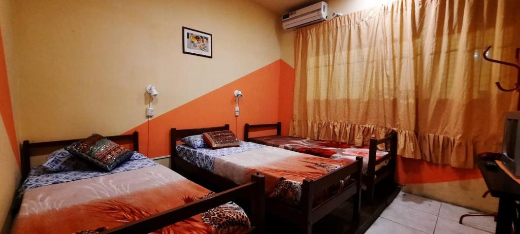 罗萨里奥Hostel en rosario的配有橙色墙壁和窗帘的客房内的两张床