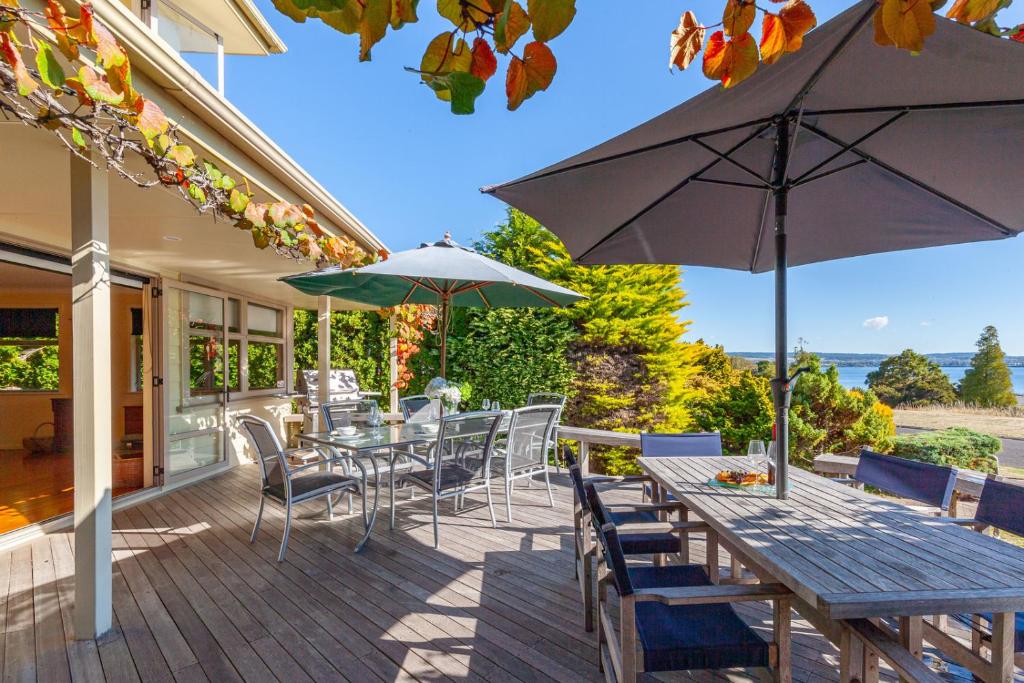 陶波Pokaka Lake House - Wharewaka Holiday Home的庭院配有桌椅和遮阳伞。