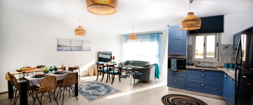 阿卡Argaman Beach Apartment的厨房以及带蓝色橱柜和桌子的用餐室。