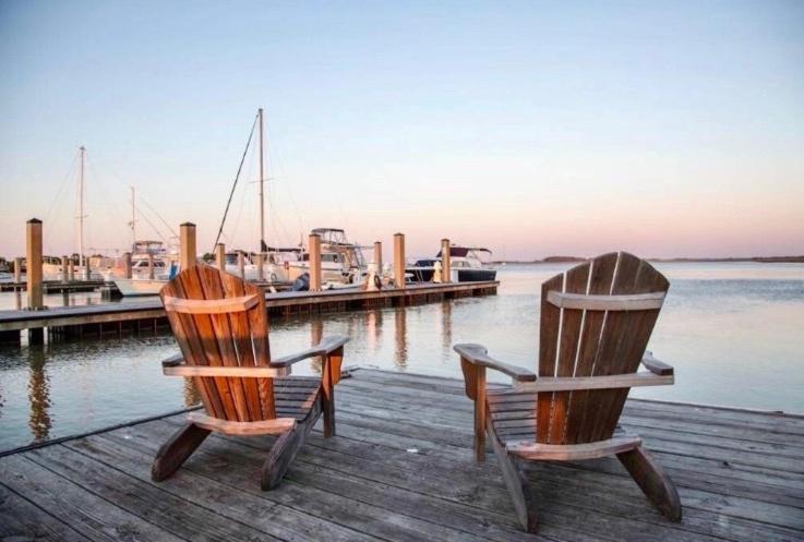 富丽海滩The Southern Harmony的两把椅子坐在靠近水面的码头上