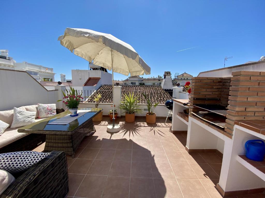 内尔哈Casa Animas Casasol Centro的屋顶露台配有桌椅和遮阳伞。