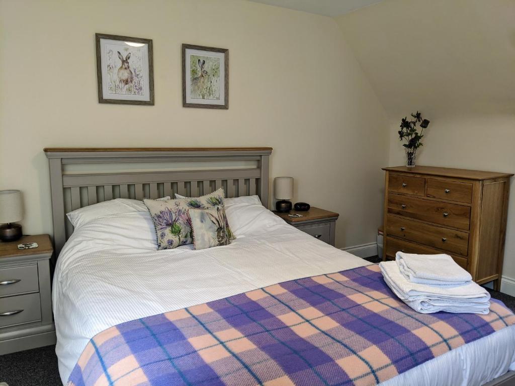 金洛赫兰诺赫Kinloch Rannoch Holiday Cottage的一间卧室配有一张带铺着平底毯的床