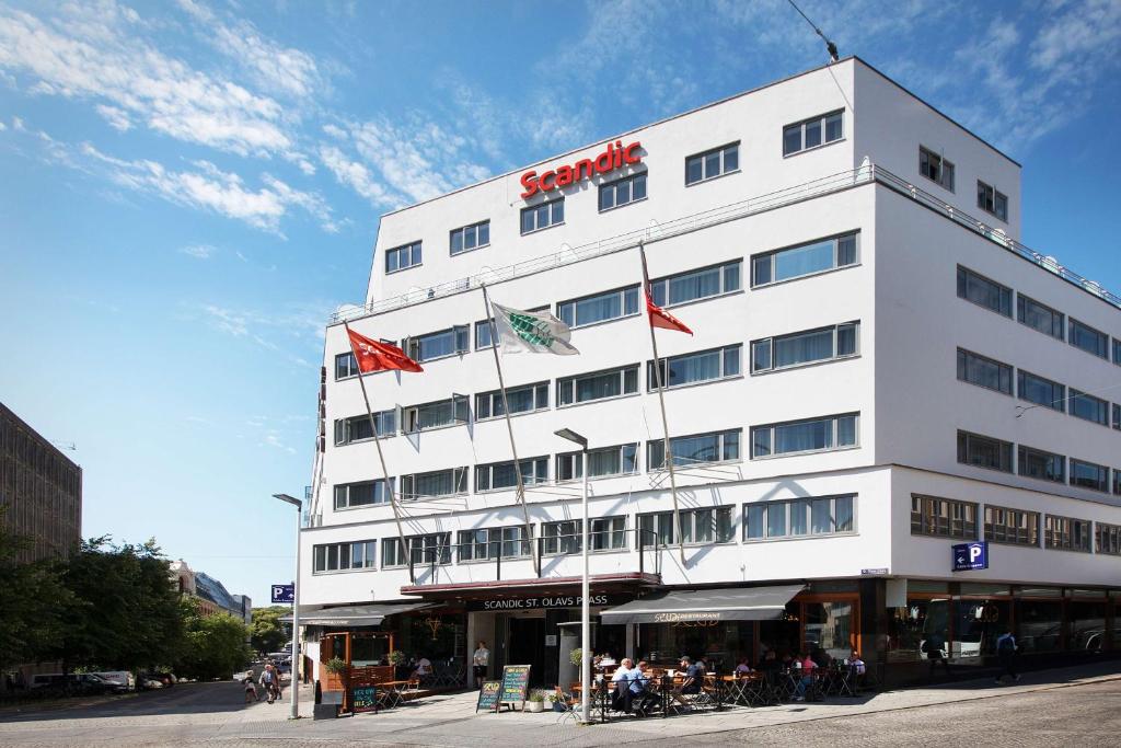 奥斯陆圣奥拉夫普拉斯斯堪迪克酒店的一座高大的白色建筑,上面有旗帜