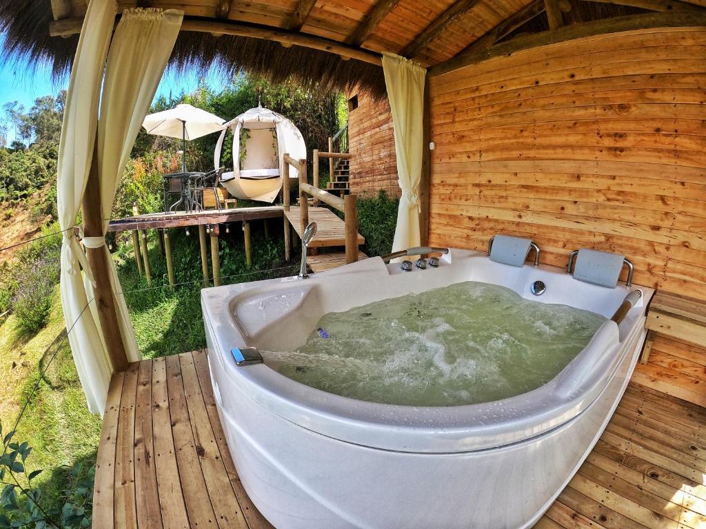 瓜塔佩Levit Glamping - Hotel Guatapé ADULTS ONLY的浴缸位于木甲板上,位于客房内