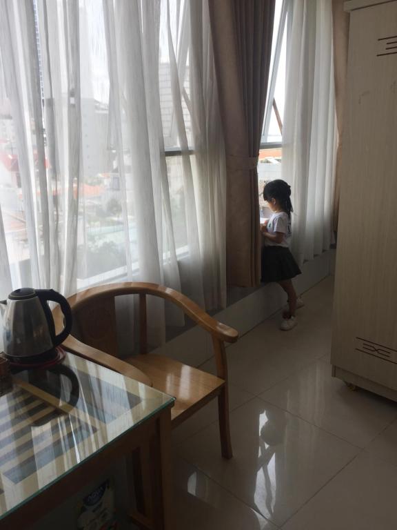 芽庄Khách Sạn Flower Sky Nha Trang的坐在椅子上,从窗户望出去的小女孩