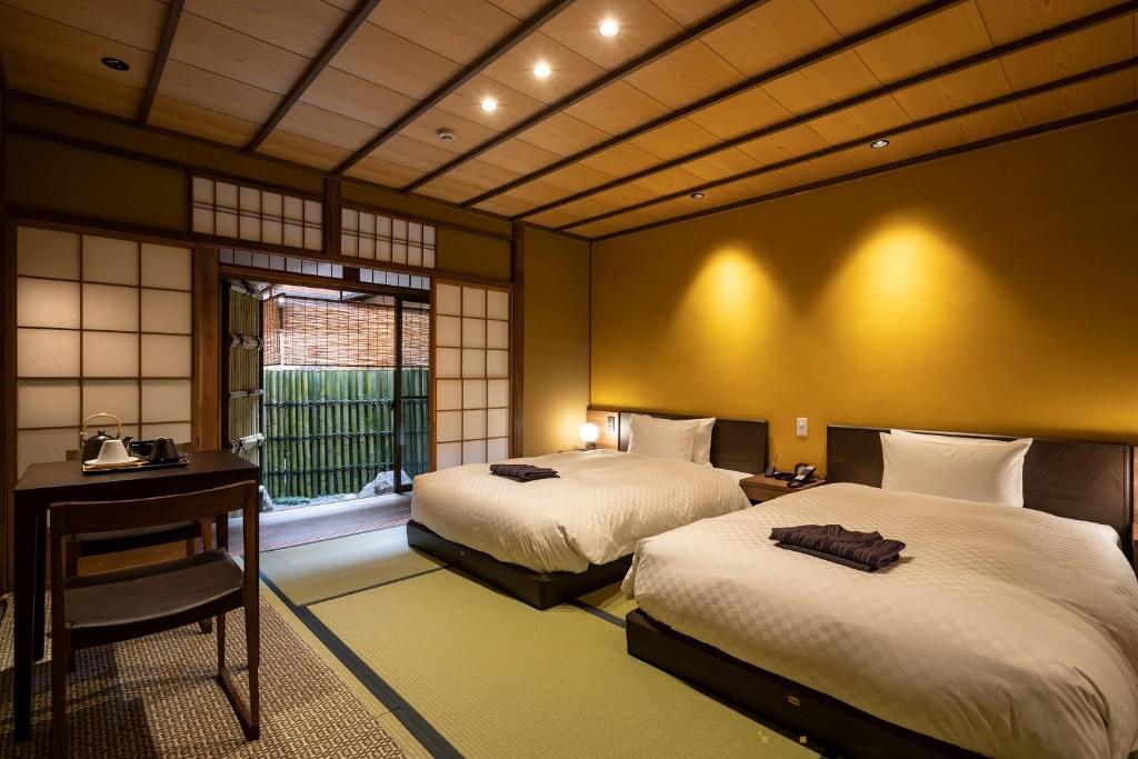 京都祇園の宿 杏花的一间卧室设有两张床、一张桌子和一个窗口。