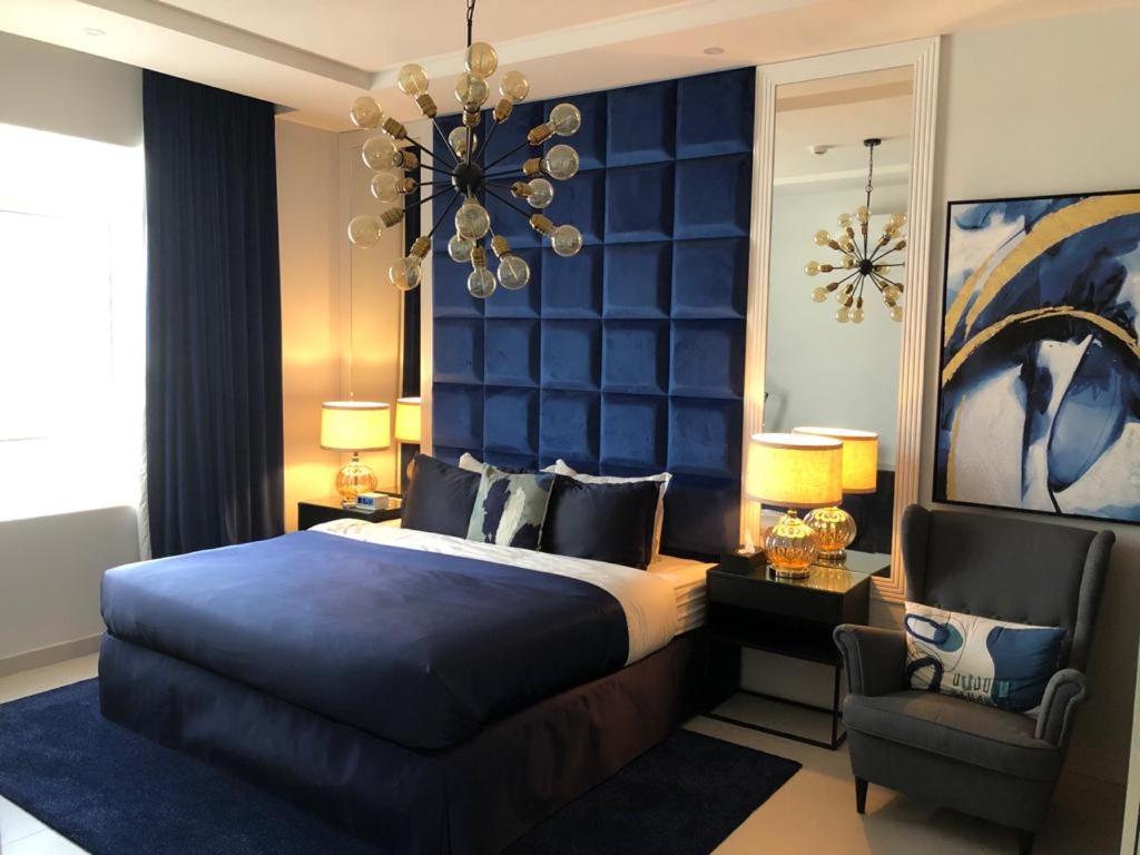 利雅德Dana Hotel & Residences 2的一间卧室配有一张床、一把椅子和一个吊灯。