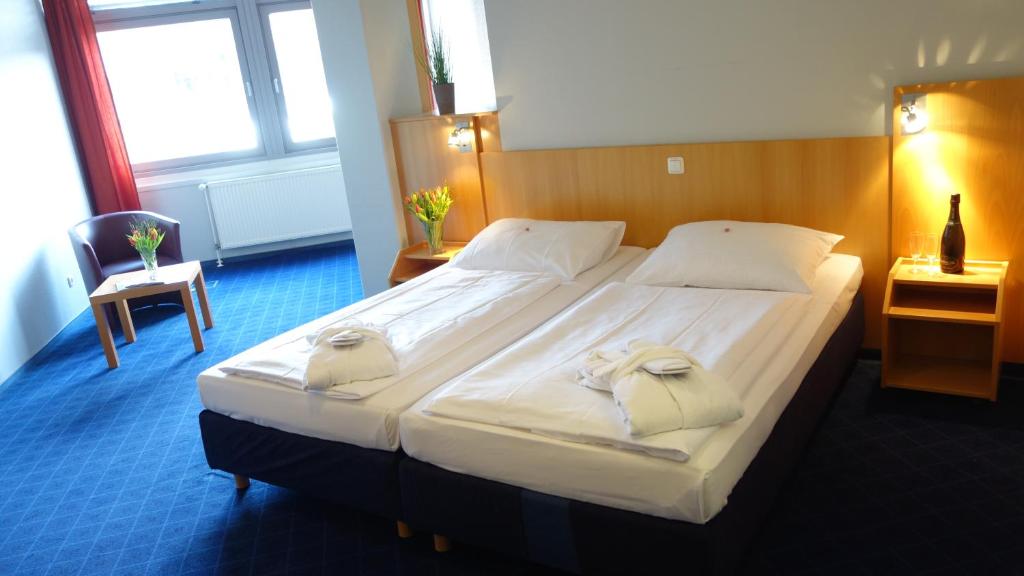 布伦瑞克Plaza Inn Braunschweig City Nord的一间卧室配有一张大床和两条毛巾