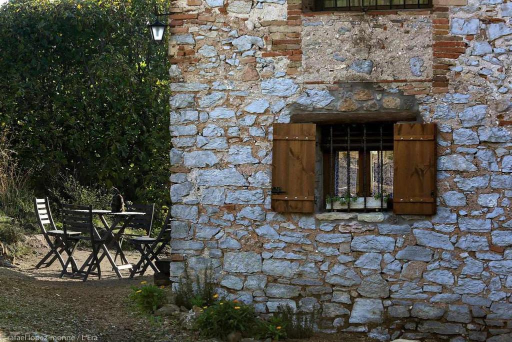 Torre de FontaubellaCasa Rural LEra的一座石头建筑,设有窗户和桌子