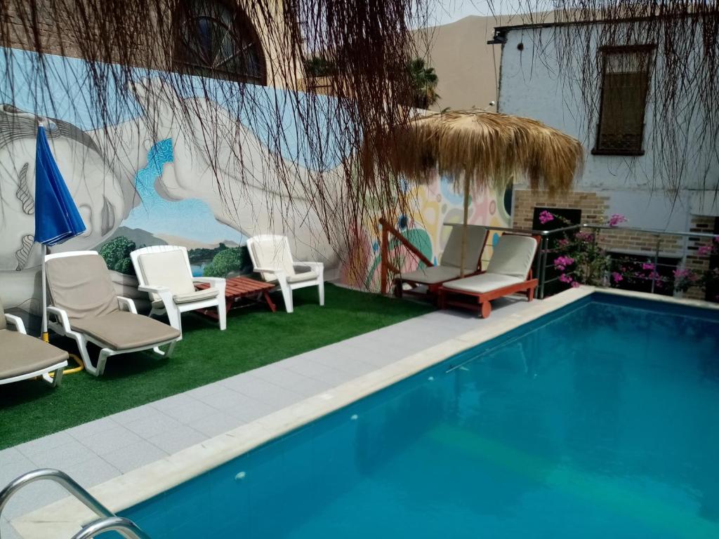 伊察瓦卡奇纳夕阳旅馆的一个带椅子的游泳池和一个带壁画的墙壁