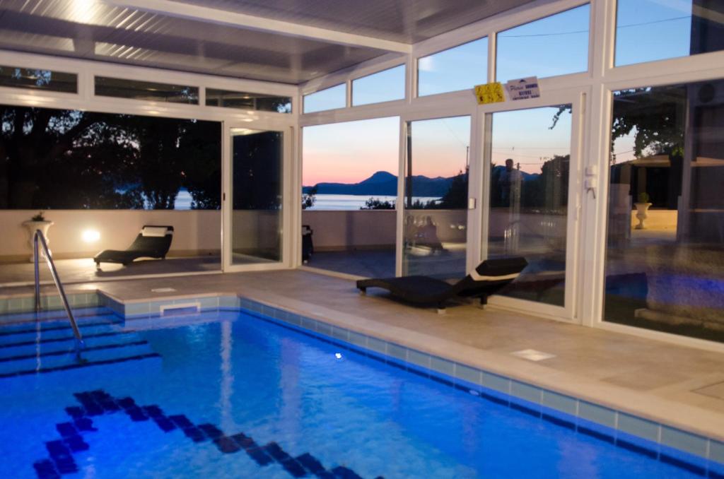 斯拉诺Apartment & Rooms Villa Katarina的一座带两把椅子的游泳池的房子