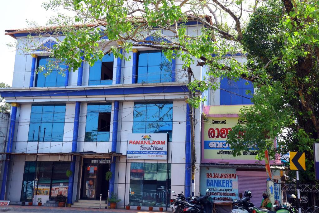 AmbalapulaiRamanilayam Tourist Home的前停摩托车的街道上的建筑物