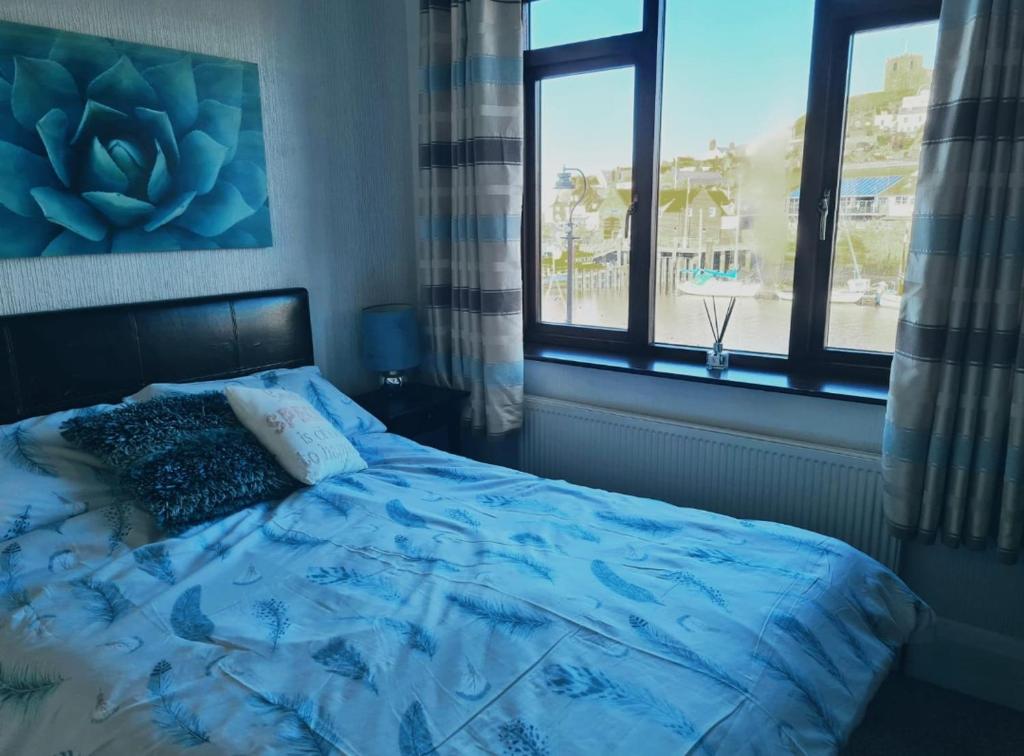 惠特比The Buck Inn的一间卧室配有一张蓝色棉被和两个窗户。