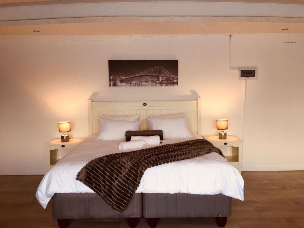乌姆塔塔Omaha Luxury B&B/Spa的卧室配有一张大床,墙上挂有绘画作品