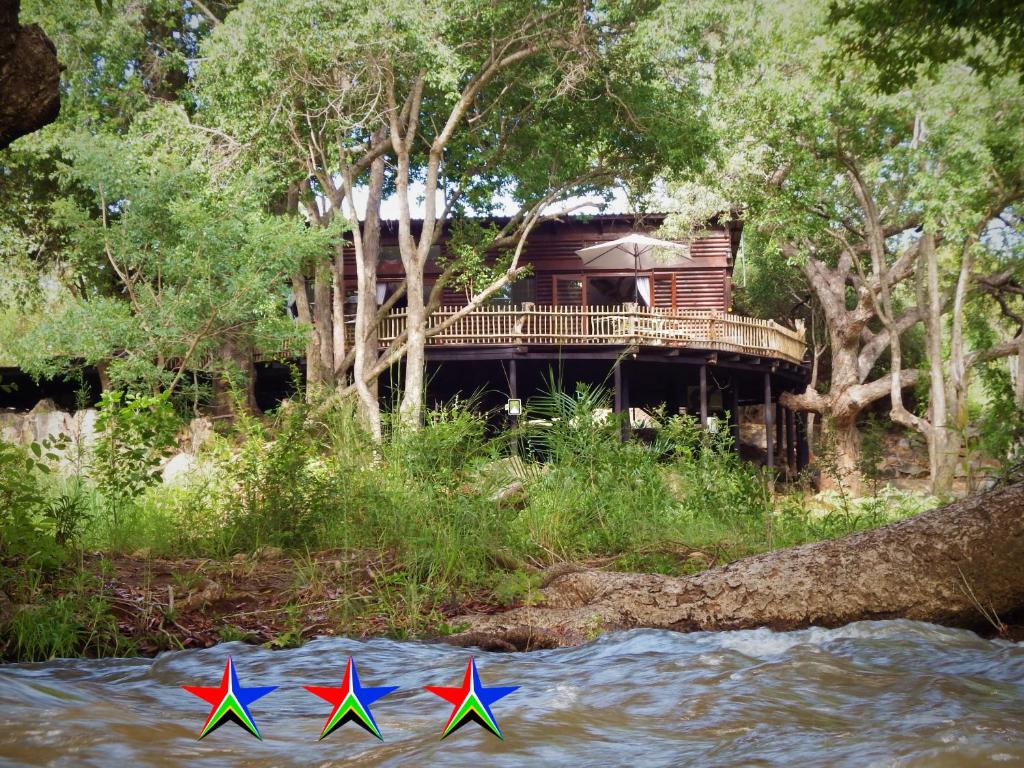 侯斯普瑞特Blyde River Cabins的水里三个五彩缤纷的风筝,旁边是房子