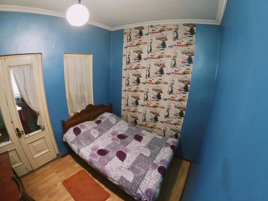第比利斯Valera Homestay的一间小卧室,配有一张床和蓝色的墙壁